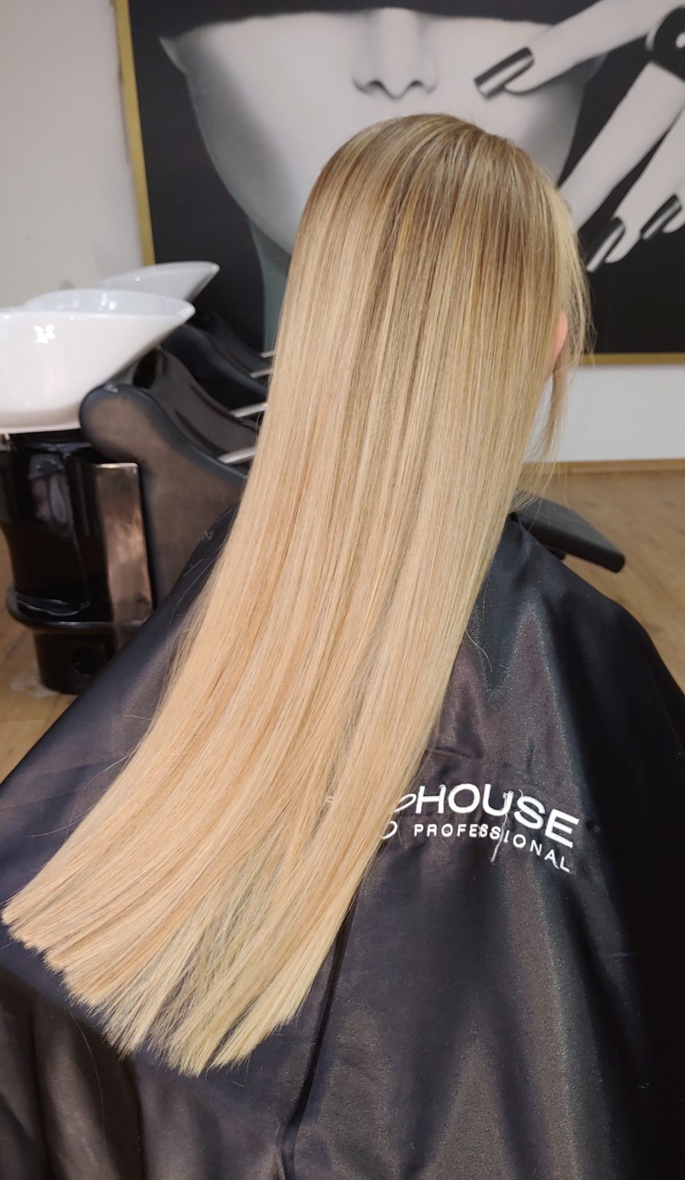 Lang, steil blond haar van achteren gezien, in de salon